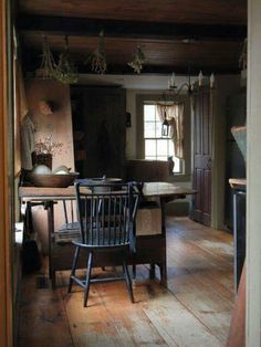 an old fashioned kitchen with wooden flooring and table in the center, looking into the dining room