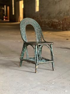 an old chair sitting in the middle of a cement floored area with no one around it