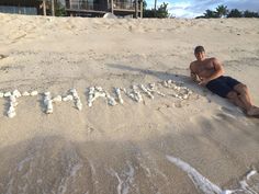 a man is sitting in the sand with his name written on it at the beach