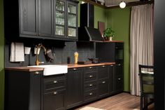 a kitchen with green walls and black cabinets