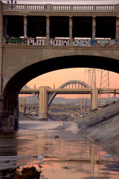 a bridge that has some writing on it and is above the water in front of an overpass