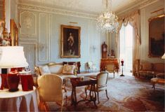 an elegant living room with chandelier and paintings on the walls