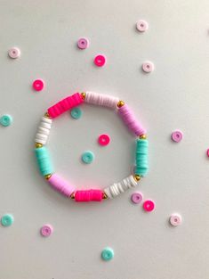 a pink and blue bracelet with white beads on it, surrounded by confetti sprinkles