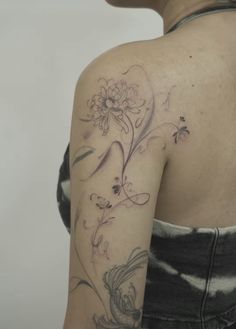 the back of a woman's shoulder with flowers and butterflies on her left arm