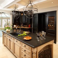 a large kitchen island with wine glasses and fruit on the counter top in front of it