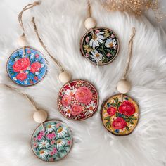 four ornaments are hanging on a white furnishing and one is decorated with flowers