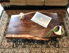 a wooden table with a laptop on top of it next to a vase and cup