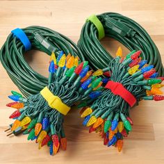 two green christmas lights on top of a wooden floor next to each other with colored lights