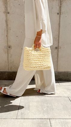 a woman walking down the street carrying a straw bag