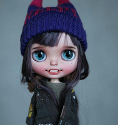 a doll with big blue eyes wearing a knitted hat