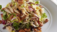 a white plate topped with a salad covered in lettuce and nuts on top of it