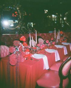 the table is set with red and white linens, silverware, candles, and flowers