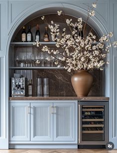 a vase filled with flowers sitting on top of a wooden shelf next to a wine rack