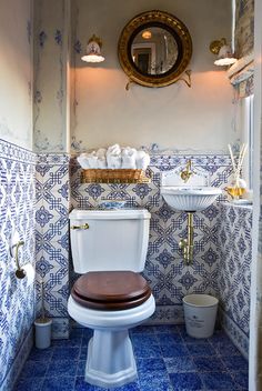 a bathroom with blue and white tiles on the walls, toilet and sink in it