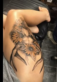 a woman with sunflowers tattoo on her thigh and leg sitting next to a black chair