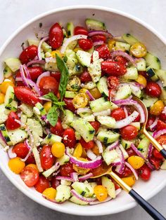 a white bowl filled with cucumber, tomato and onion salad