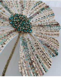 a close up of a decorative object made out of beads and sequins on a white surface