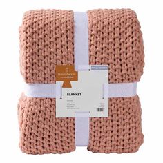 the blanket is pink and white with a brown tag hanging from it's side