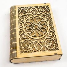 a wooden book with intricate carvings on the front and back cover, sitting on a white surface