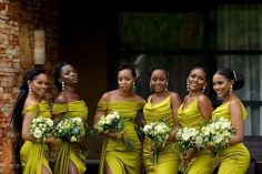 a group of women standing next to each other wearing yellow dresses and holding bouquets