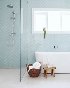 the bathroom is decorated in blue and white with herringbone tile on the walls, along with a claw foot tub