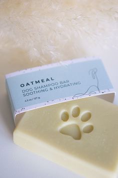 an oatmeal soap bar next to a dog's paw stamp on a white surface