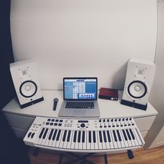 a laptop computer sitting on top of a desk next to a keyboard and sound equipment