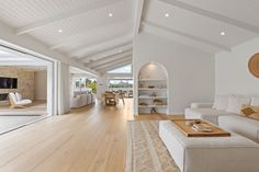 an open living room with white furniture and wood flooring is seen in this image