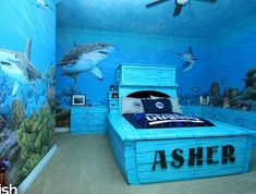 a bedroom with shark themed walls and blue bedspread, under the sea floor