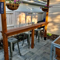 a wooden table sitting under a hanging planter on top of a patio next to a fence