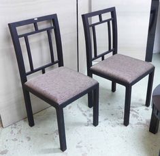 two chairs sitting next to each other in front of a wall with white tiles on it