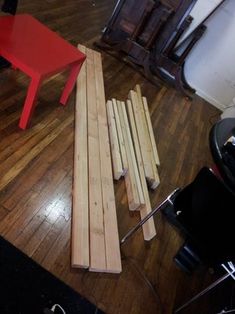 several pieces of wood sitting on top of a wooden floor next to a red chair