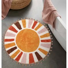 a round rug on the floor in front of a bathtub with a pink towel next to it