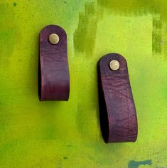 two wooden hooks on a green wall with yellow and green paint in the back ground