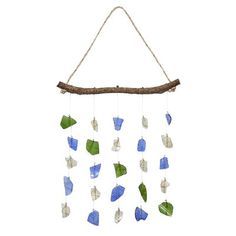 a wind chime hanging from a tree branch with sea glass pieces in the shape of boats