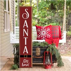 a wooden sign sitting on top of a porch next to a christmas tree and other decorations