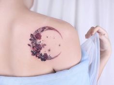 a woman with a tattoo on her shoulder that is decorated with flowers and stars in the shape of a crescent