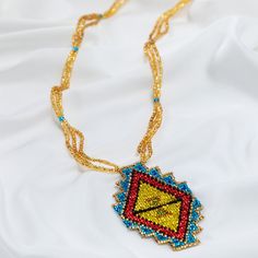 Trendy and tribal-inspired, the Mayan Pyramid Beaded Pendant Necklace makes a bold statement. Perfect for pairing with whites or denim for a great boho look. Made by women artisans of La Casa in Guatemala. Since 2000, La Casa Cotzal has designed a range of Guatemalan handcrafted pieces produced by artisan communities throughout the country. Mayan women traditionally have been backstrap loom weavers, but increasingly they are learning to use pedal looms as well. In traditional Guatemalan weaving, the two main specialized techniques are ikat and supplementary weft brocade. Artisans at La Casa are versed in both weaving techniques as well as in intricate bead work. The work provided by La Casa is vital to the women's families and communities. Glass beads & cotton thread Pendant: 3.25" H x 2" Artisan Beaded Jewelry For Festivals, Artisan Beaded Jewelry For Festival, Gold Beaded Necklace For Festival, Artisan Beaded Chain Jewelry For Festivals, Artisan Jewelry With Beaded Chain For Festivals, Bohemian Beaded Chain For Crafting, Bohemian Gold Beads For Festival, Bohemian Pendant Beaded Necklaces With Gold Beads, Bohemian Necklace With Gold Bead Pendant