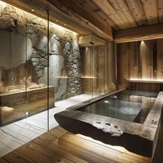 an indoor hot tub in the middle of a room with stone walls and wooden floors