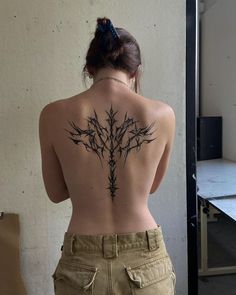 a woman with a tattoo on her back is standing in front of a table and chair