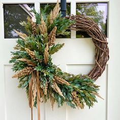 a wreath is hanging on the front door with two wooden sticks and some green leaves