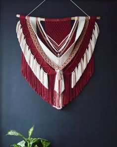 a red and white wall hanging next to a potted plant