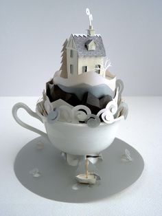 a tea cup with a house on top