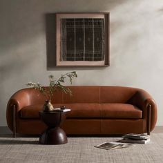 a living room with a couch, table and potted plant on the floor next to it