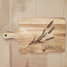 a wooden cutting board with the words, thankful written in black ink on it