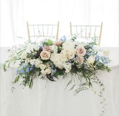 a table with flowers and greenery on it is set up for a wedding reception