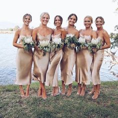 a group of women standing next to each other on top of a grass covered field