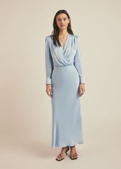 a woman is wearing a blue dress with long sleeves and an asymmetrical neckline