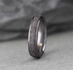 the wedding band is made out of silver and has a textured design on it