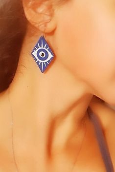 a close up of a woman's face wearing earrings with an evil eye on it